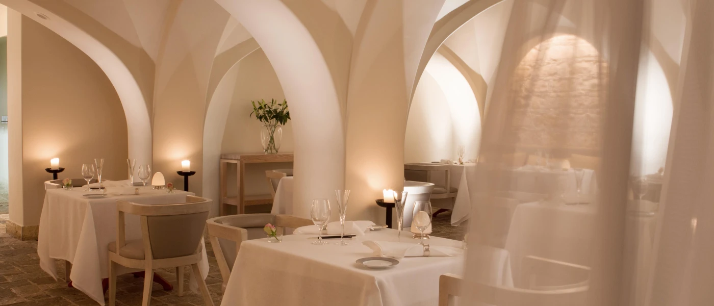 Romantic restaurant with curved white walls, sheer white curtains, crisp white tablecloths and lantern and candlelight