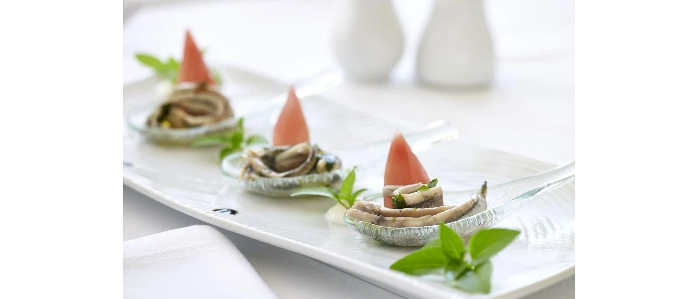 White platter with three stacks of seafood, piled up in shells with sprigs of mint
