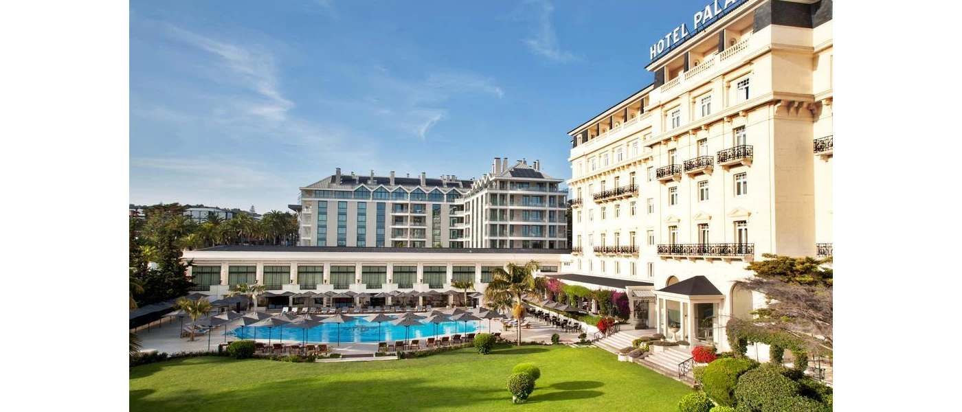 Palacio Estoril's grand white facade and black balconies, overlooking the swimming pool and lawned gardens
