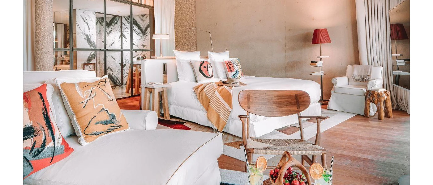 White daybeds with bohemian printed cushions, a wooden stall and seating and a basket of fruit