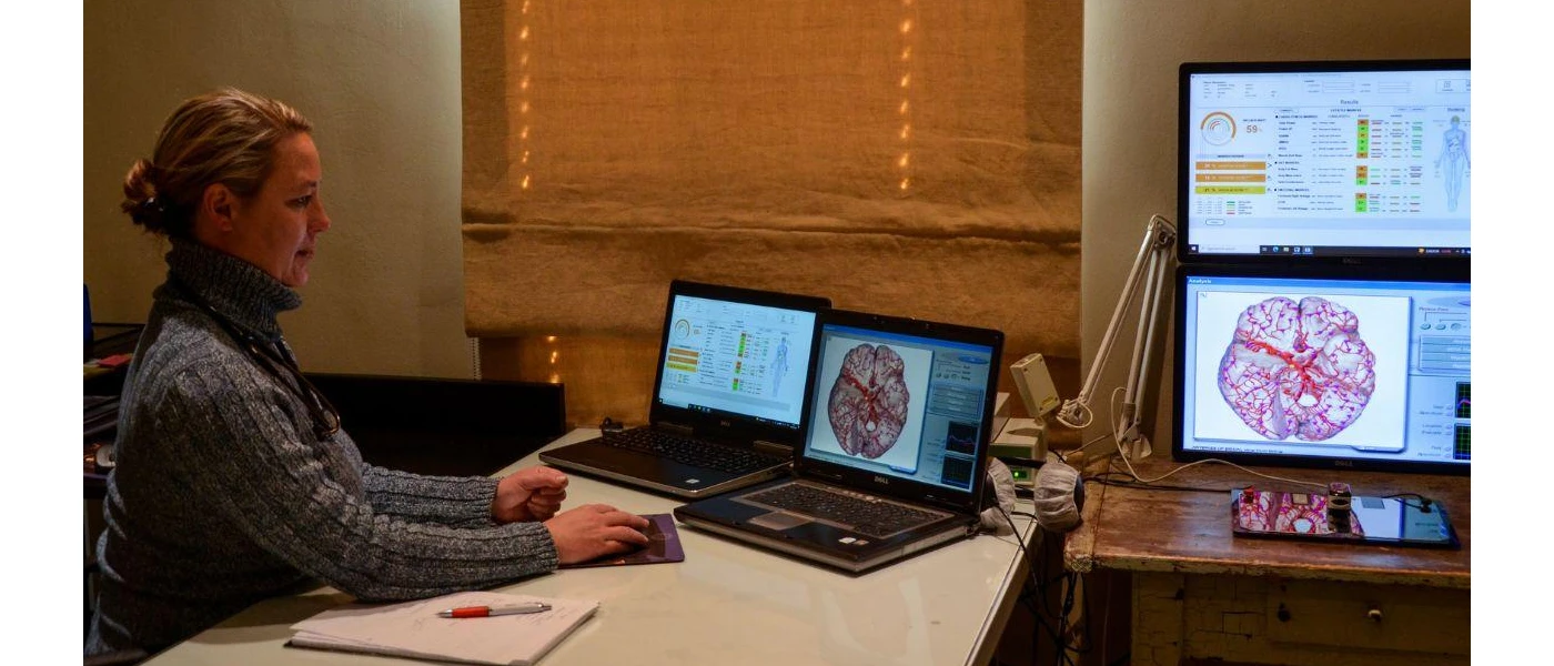 A healthcare professional surrounded by screens showing scans as she sits at a desk