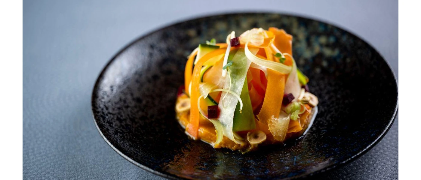 Colourful vegetables presented in a stacked mound on a black bowl