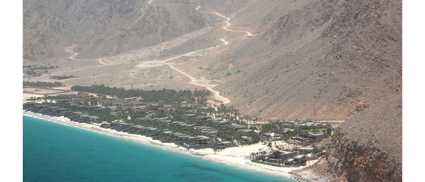 Dark-roofed resort at the foot of the mountains, on a white-sand beach and lapped by the sea