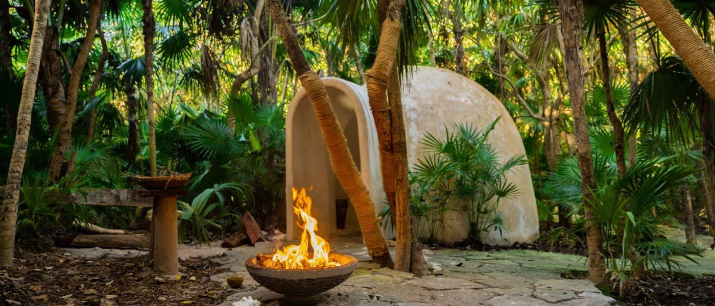 Fire pit and domed cave-like structure in the middle of tropical jungle