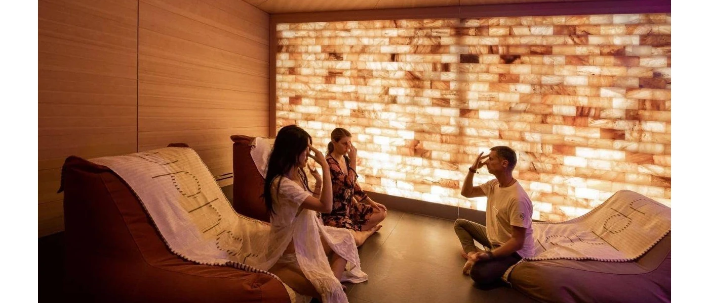 Three people in a softly lit room sit on bean bag chairs with their hands on their faces