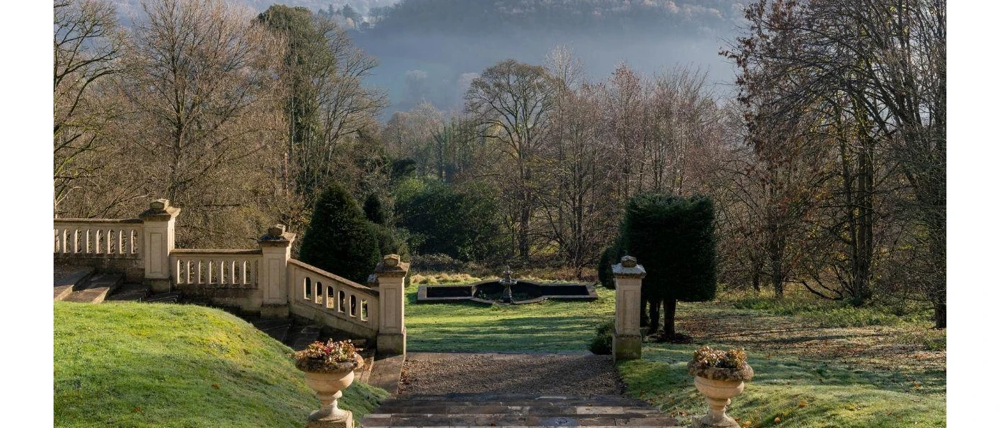 Grand concrete wall and stone pathway lined with lawns and leafy trees