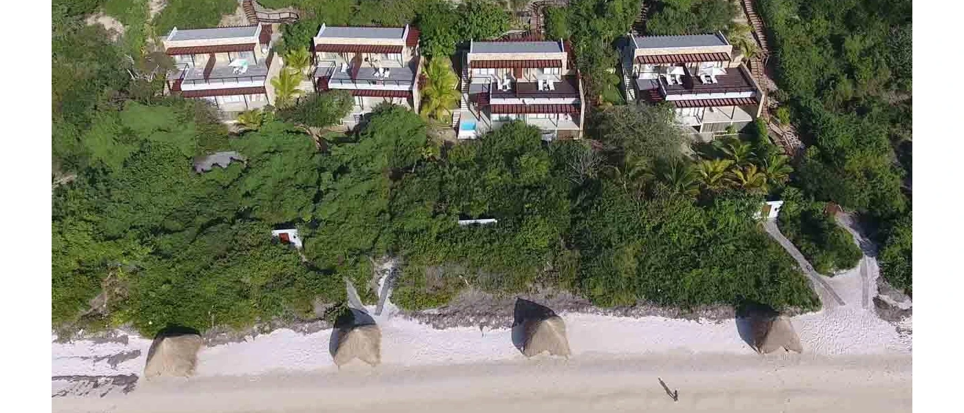 Luxury suites overlooking a white beach and surrounded by greenery