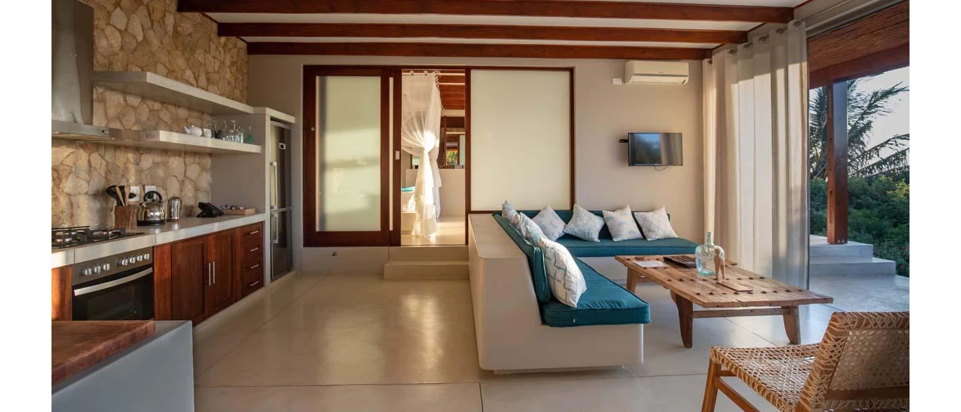 Blue and white cushioned seating area and kitchenette with stone wall backing
