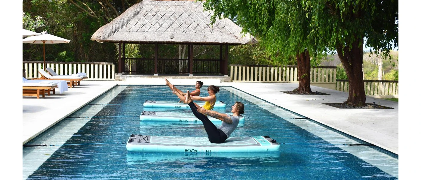 Three women on suspended mats in a swimming pool with their arms and legs outstretched