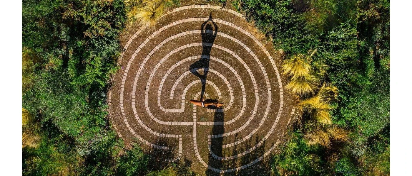 Woman in a yoga pose on a patterned terrace surrounded by gardens