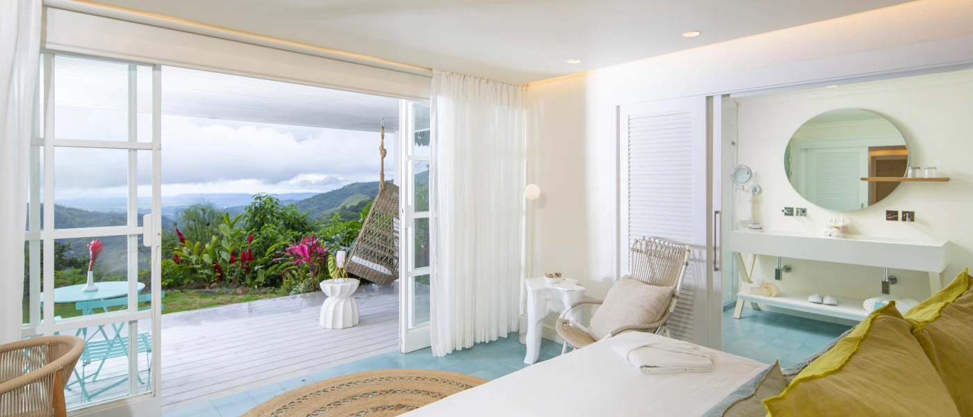 Minimalist hotel room with white walls looking out to a terrace with 