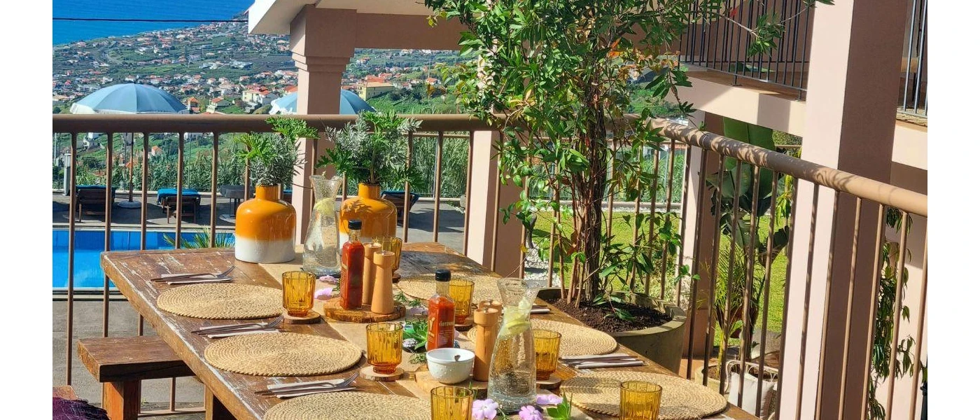 Outdoor wooden table in the sunshine with a view of the pool area and surrounding countryside