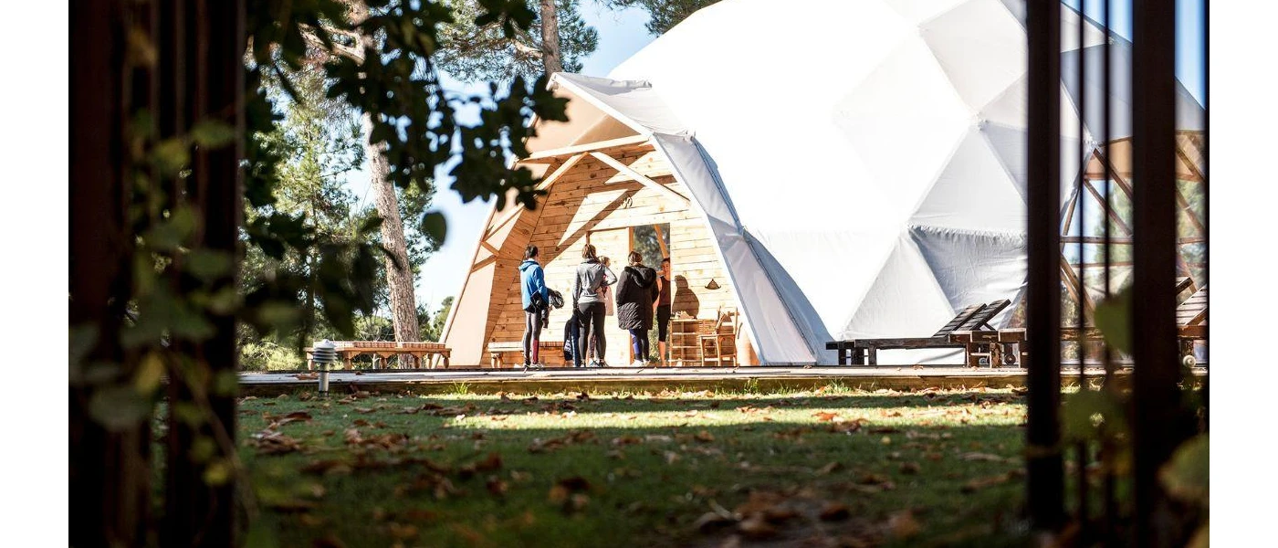 Group of people stand outside a domed white structure in a garden