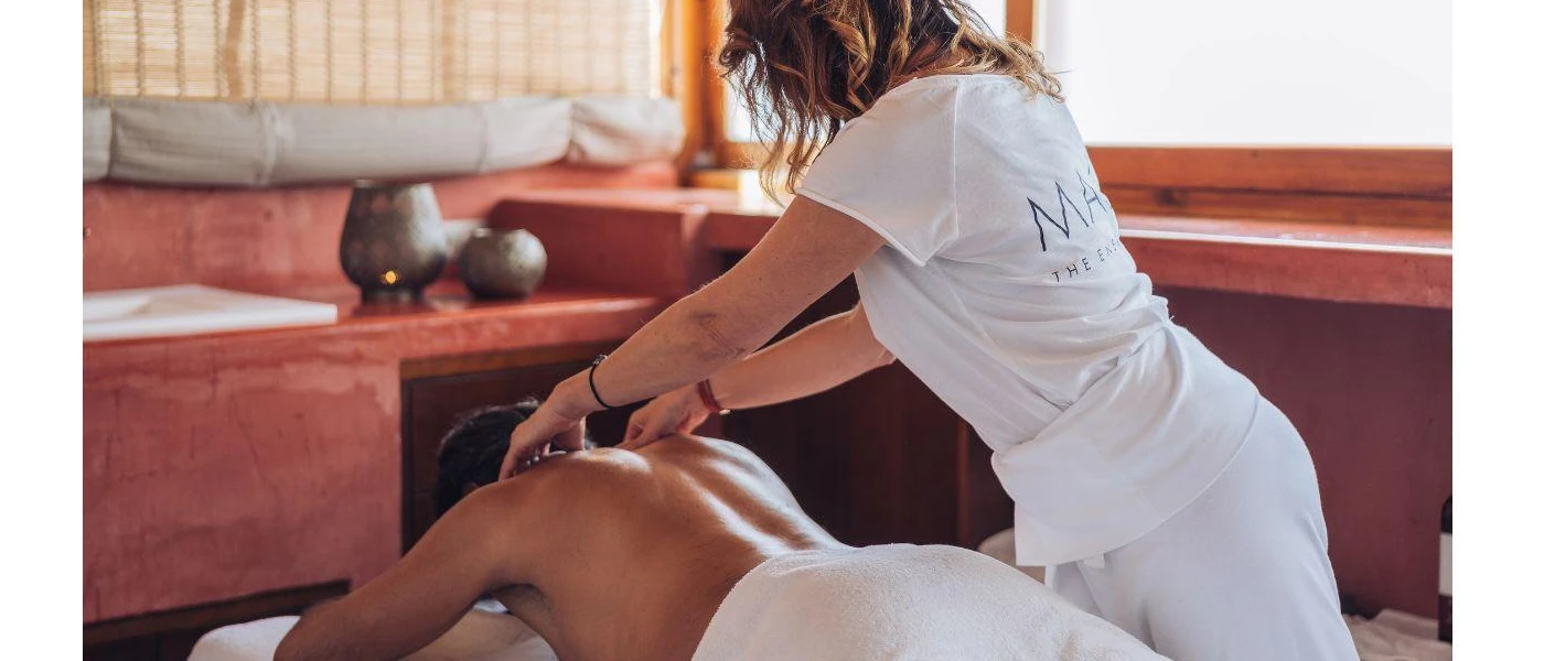 Person lies on their front a a therapist in white massages their back