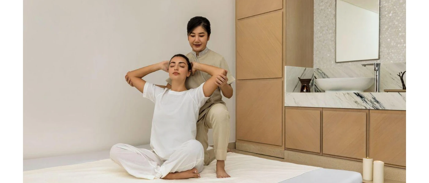 Woman in white leans back as a therapist pulls her arms backgrounds during a spa treatment