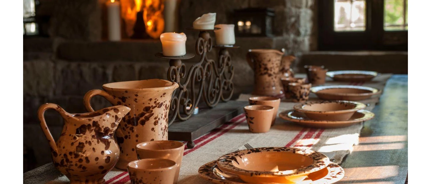 Wooden table laid up with terracotta pouring jugs, plates and cups and an intricate candleabra