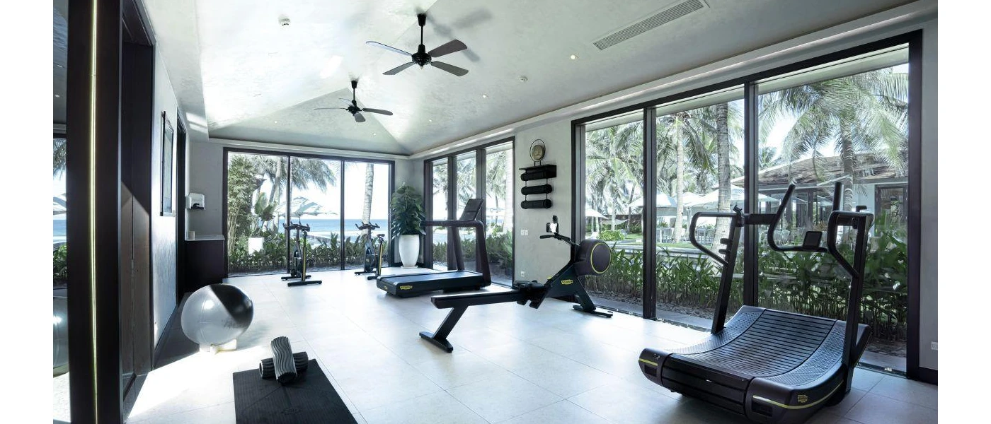 Gym with full-length windows and a running machine, treadmill, rower and yoga mat