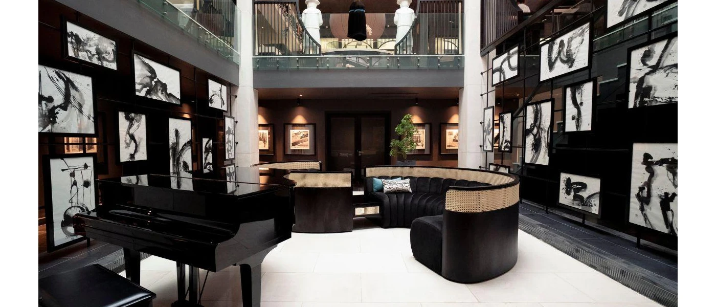 High-ceiling room with black walls, black and white pictures, a black piano and two large white pillars