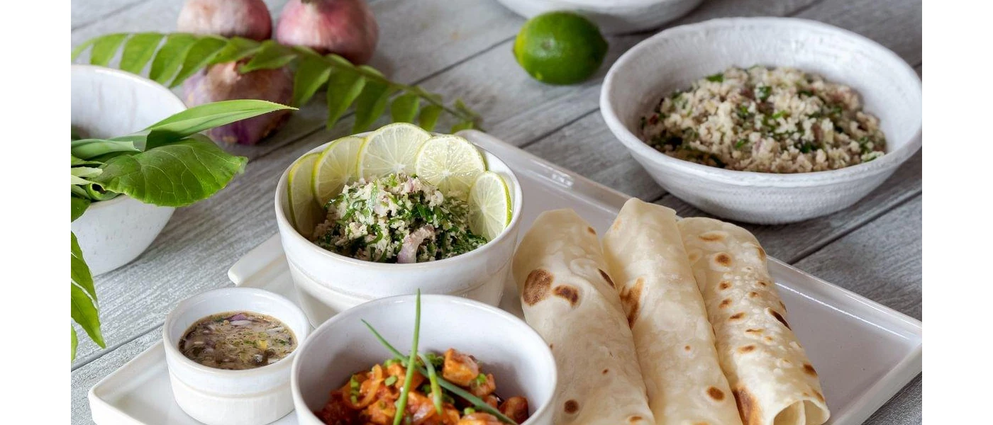 Toasted wraps rolled up next to bowls of salad, one with a lemon garnish