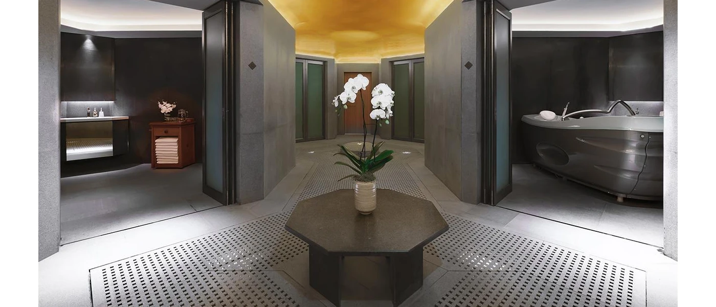 Central room in a spa, with a table and orchids on top, looking into treatment rooms