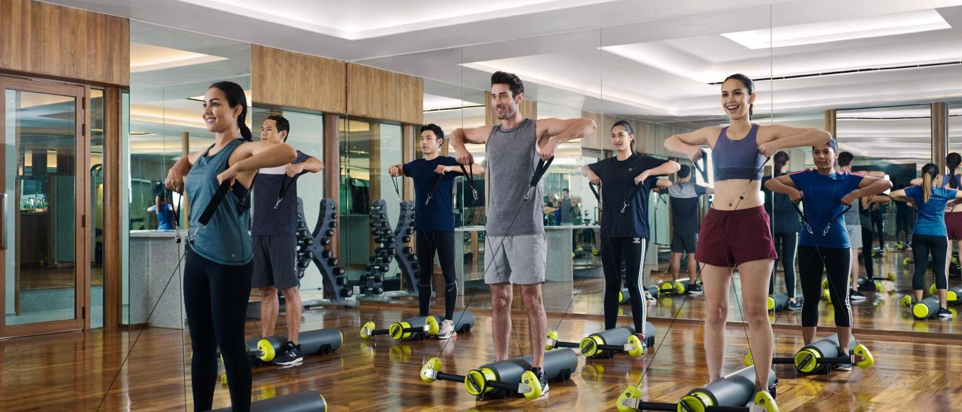 Group of smiling people in active wear using resistance-style apparatus in a gym studio