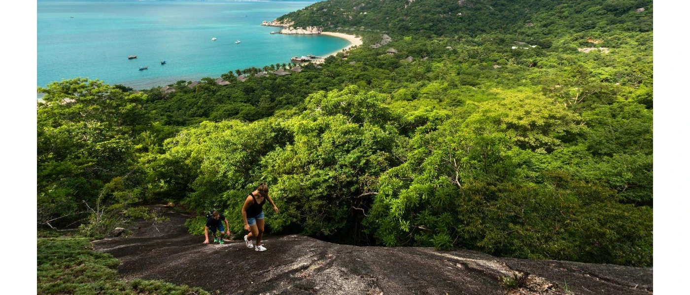 Couple in black tops and denim shorts hiking up a dark rockface 