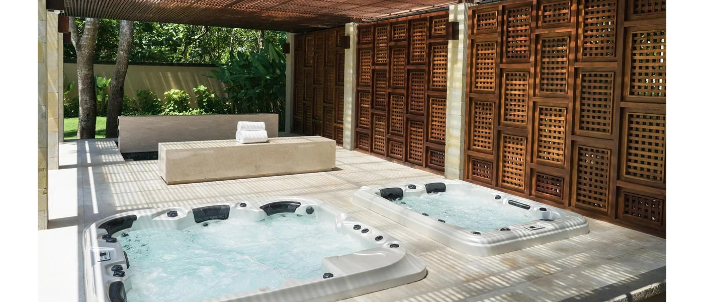 Two whirlpool baths in wooden decking next to a dark-wood panelled wall