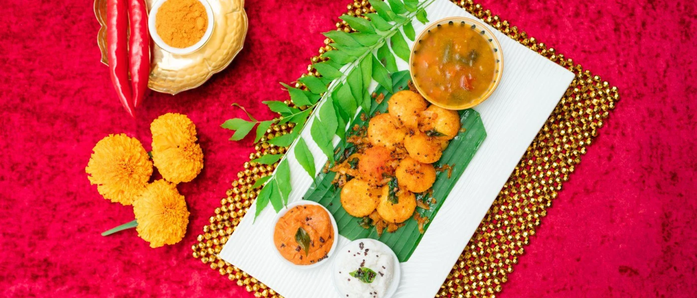 Orange coloured food laid out next to orange flowers and a leaf on a white plate
