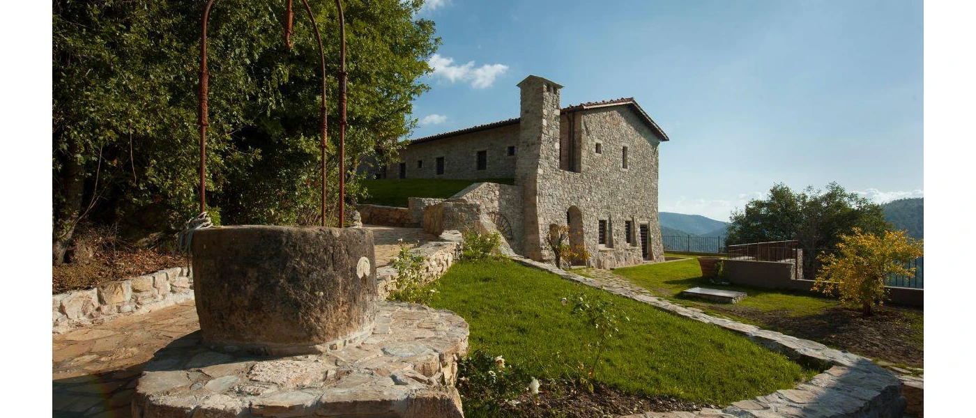 Histori farmhouse-style stone building with a grassy lawn and surrounding trees