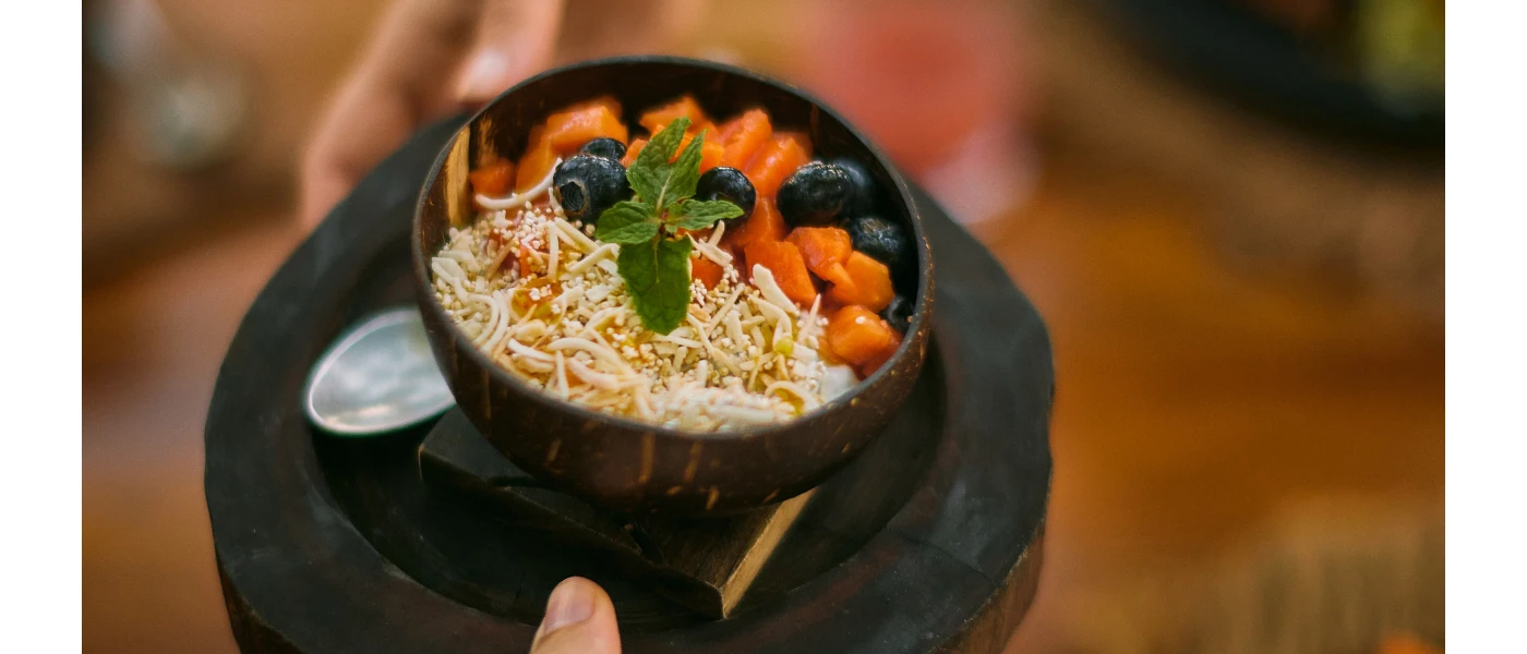 Waiter carrying a black poke bowl topped with a sprig of mint