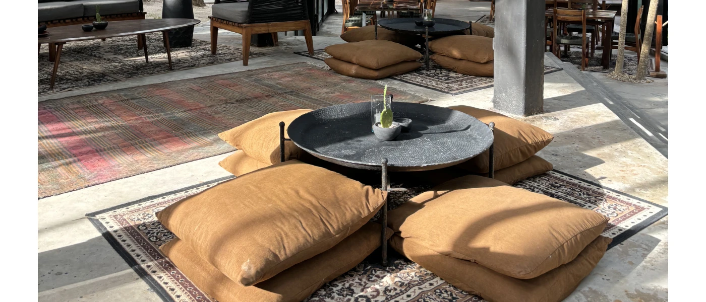 Brown square floor cushions around a round low table on a patterned rug