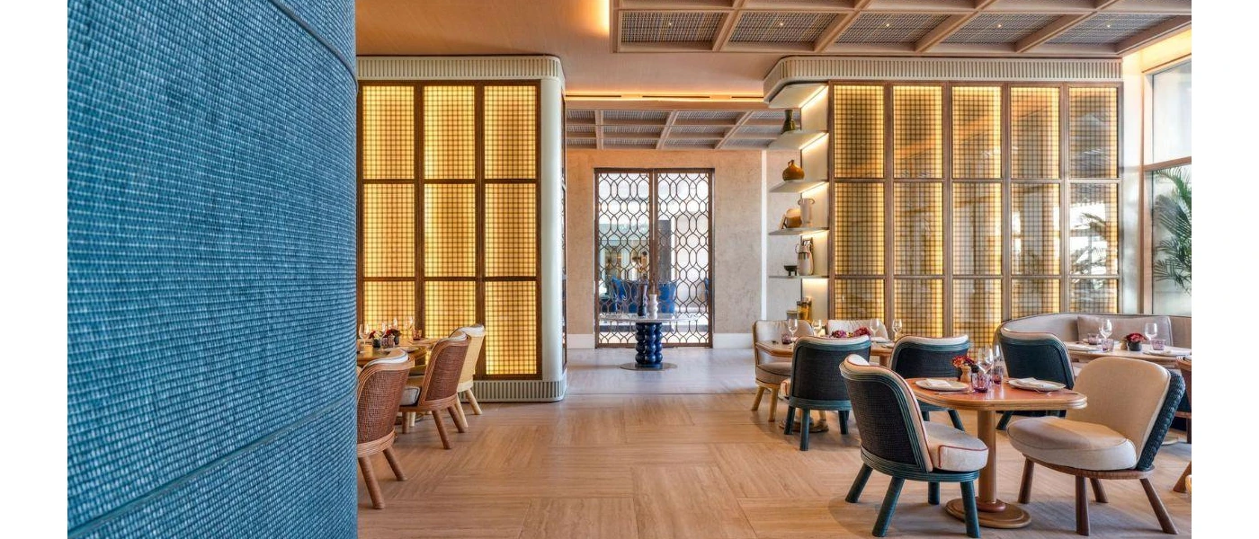 Airy restaurant with tables and chairs and soft lighting down the walls