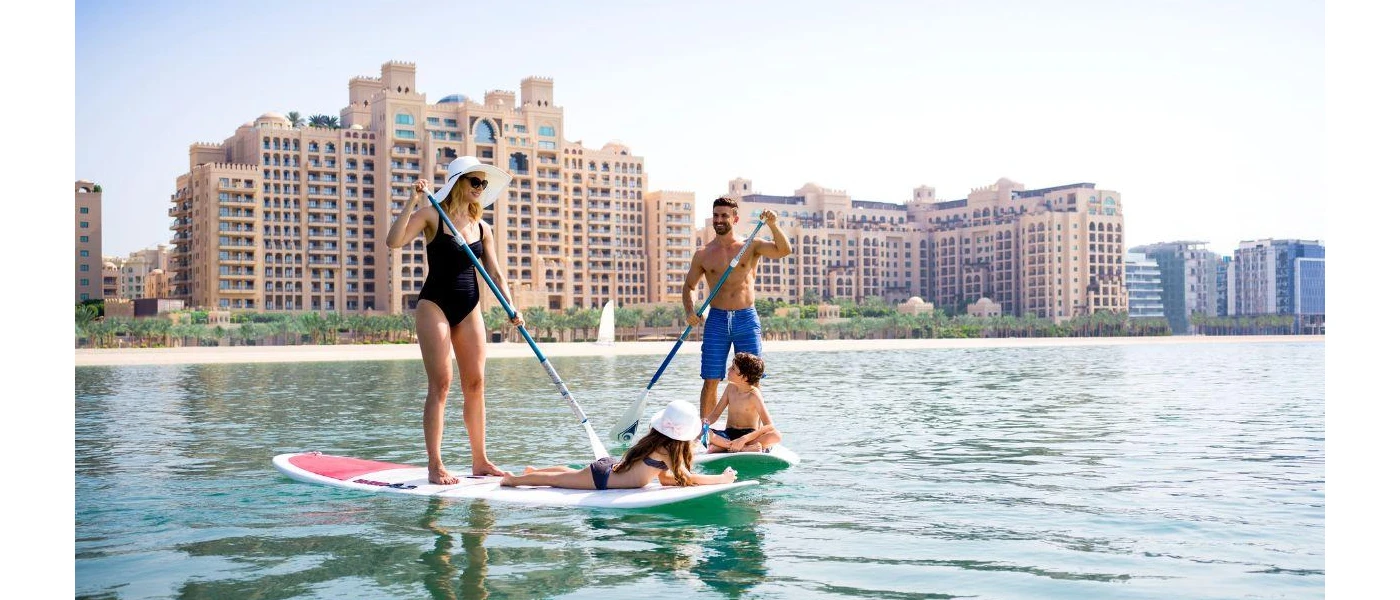 Smiling family paddle board in the sea in front of Fairmont The Palm