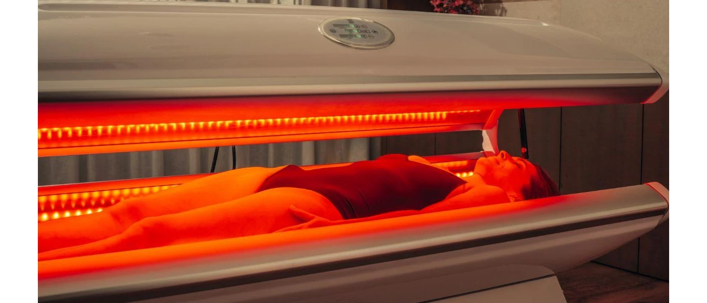 Female in a black swimsuit lies in a lounger with red infrared lighting