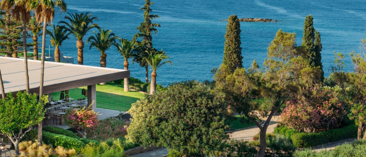 Tropical gardens on a hillside overlooking the sea, with an al fresco terrace laid up for dining
