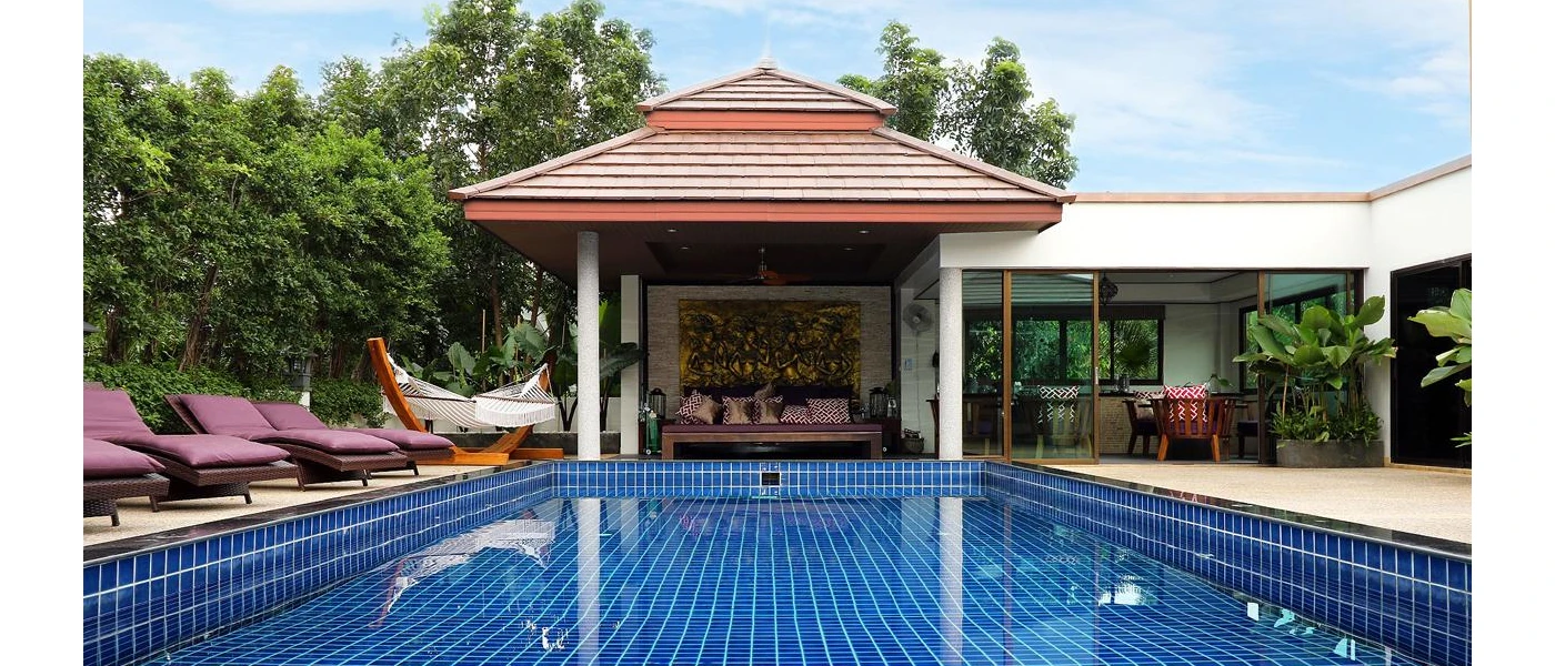 Tiled swimming pool surrounded by purple-cushioned loungers, a hammock and a pagoda with a sofa