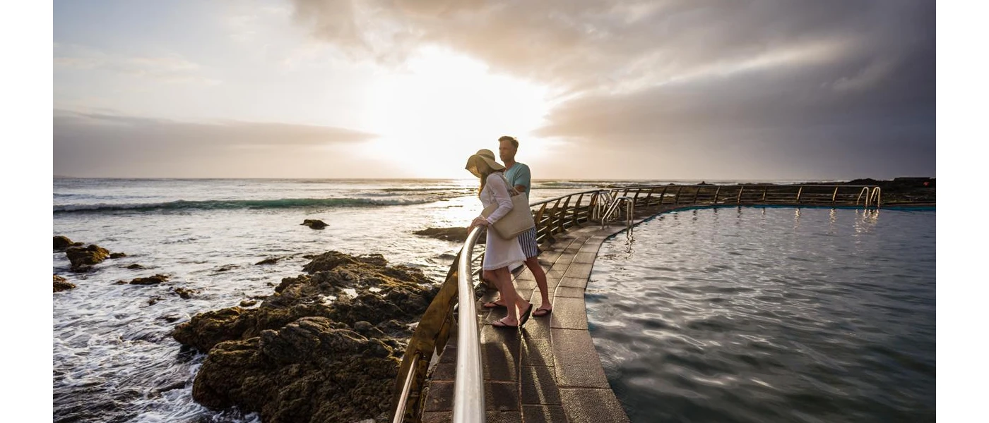 Couple enjoying the view at the seafront as the sun goes down
