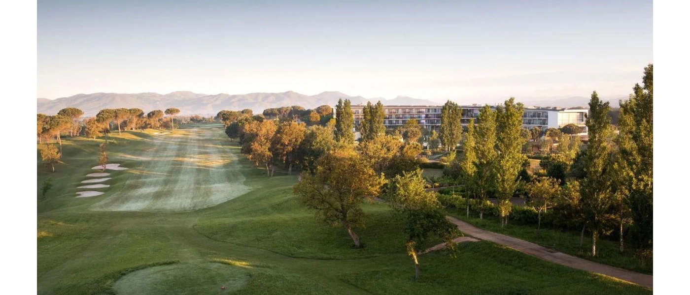Golf greens surrounded by trees and mountains