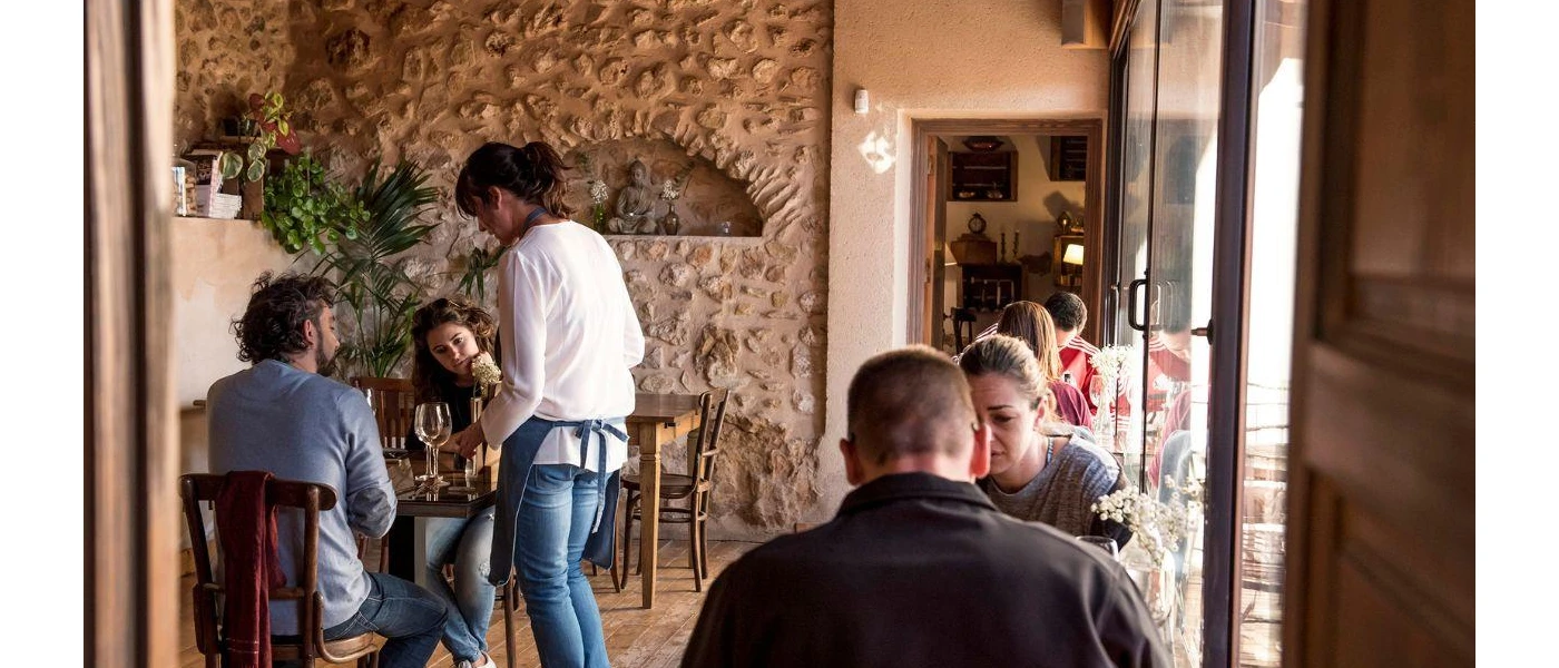 Traditional restaurant with cobbled stone walls, wooden furniture and guests sitting down at tables