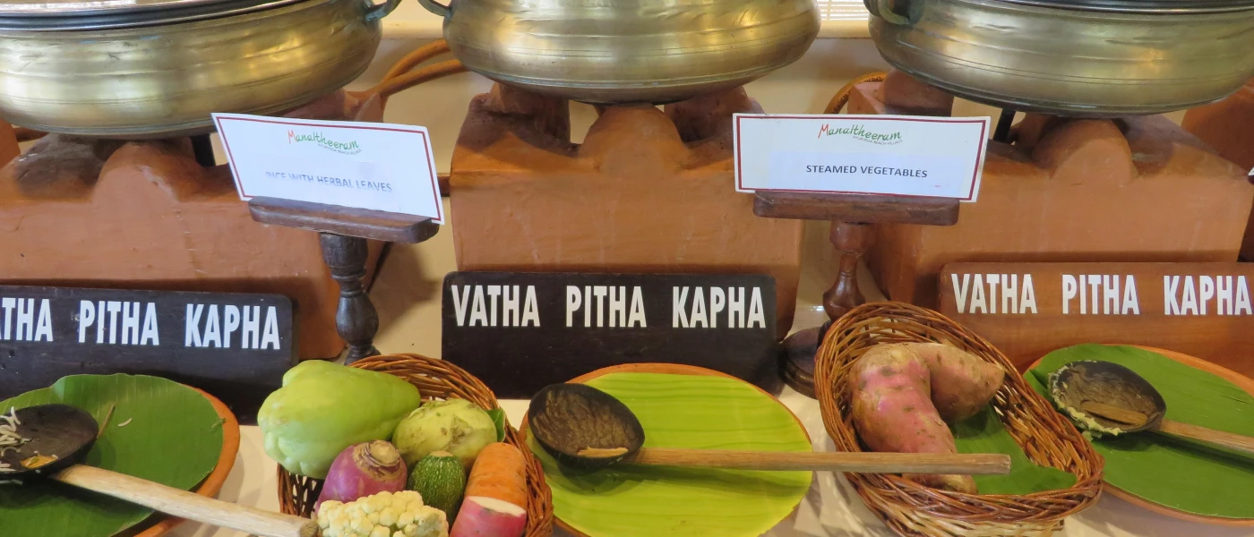 Silver pots laid out buffet-style with signs that read 'steamed vegetables' and 'rice with herbal leaves'