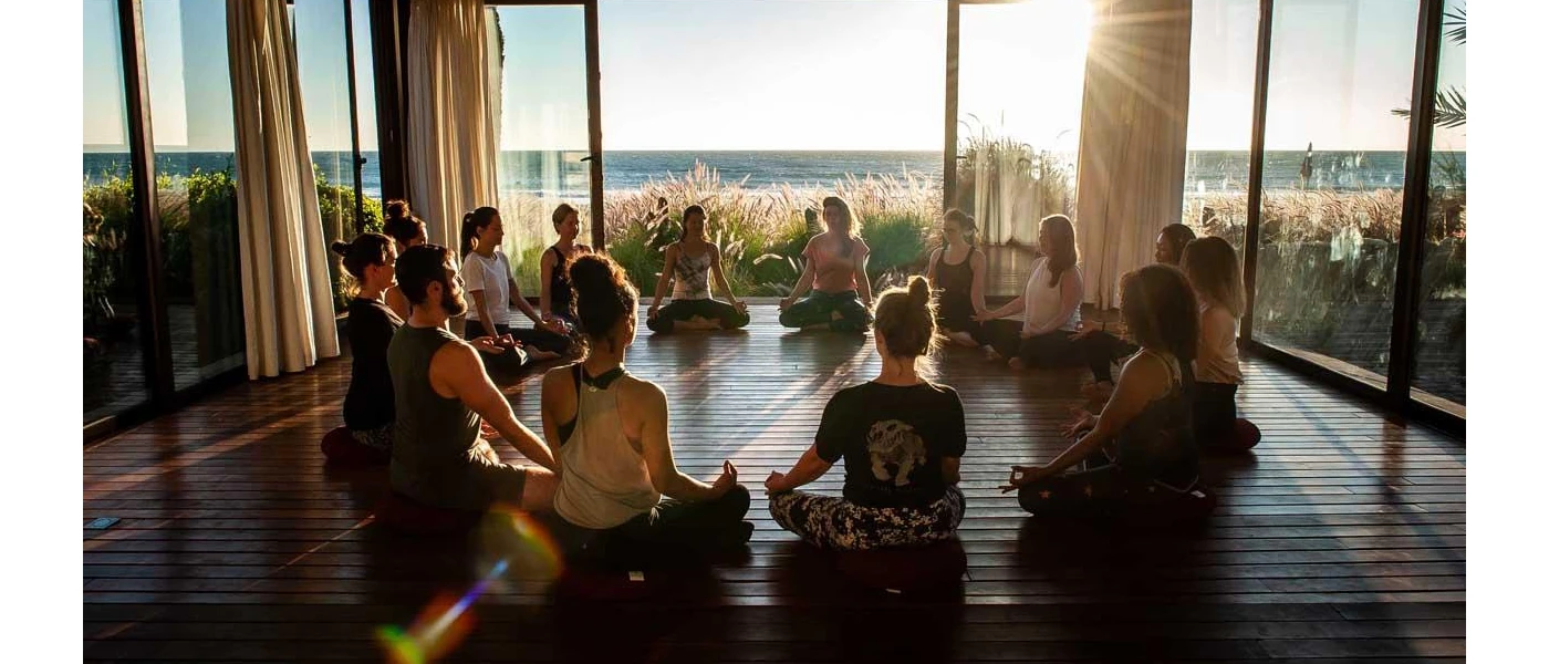 Group in a circle in a studio overlooking the sea as the sun rises