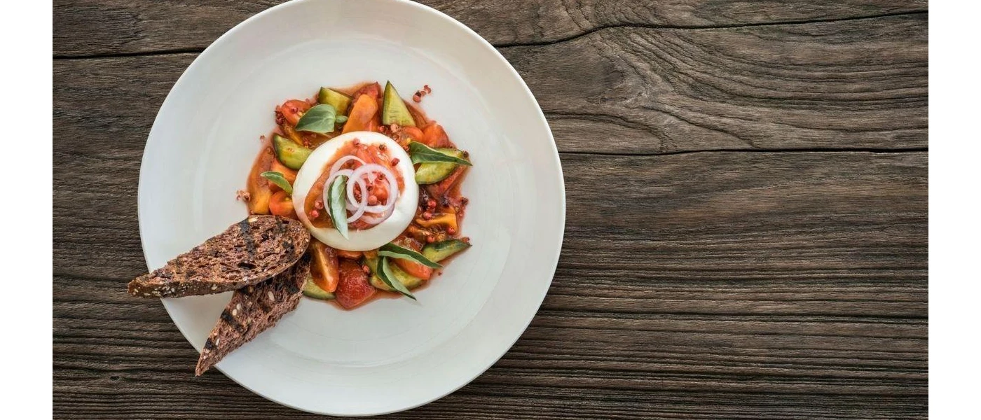 A white plate with colourful vegetables, seeded bread and onion garnish