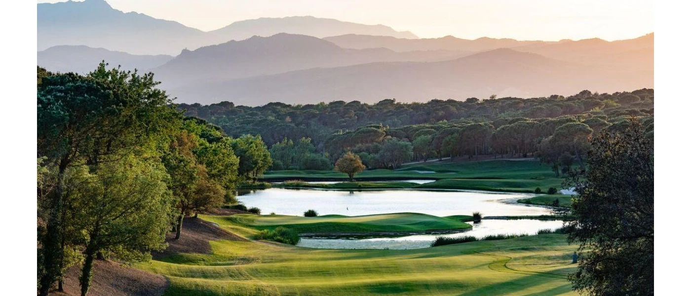 Golf greens with a lake in the middle surrounded by thick forested greenery