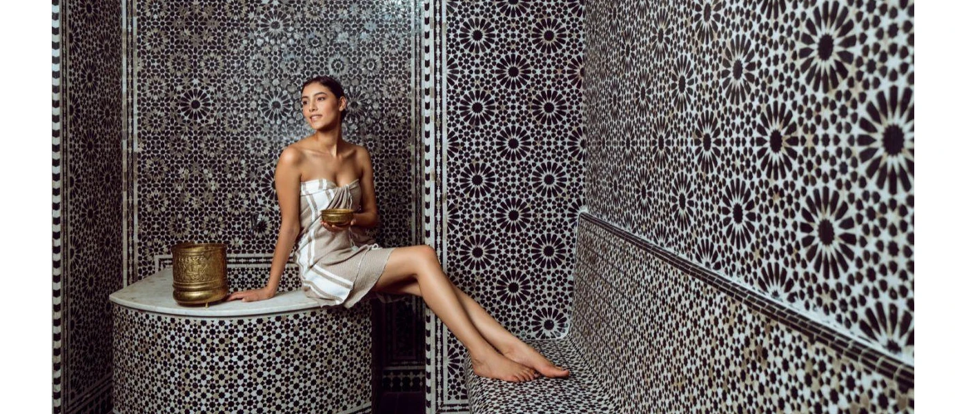 Woman relaxing in a towel in a black and white tiled steam room
