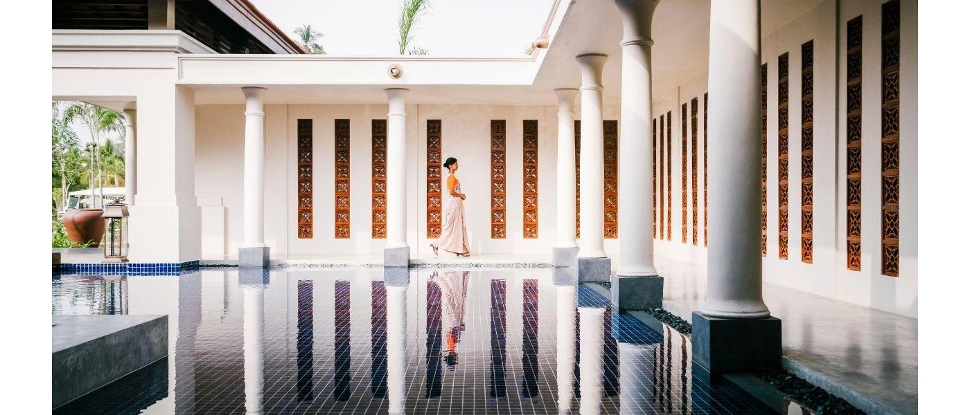 Woman in Sri Lankan dress walking past an indoor water fountain in a room filled with white pillars