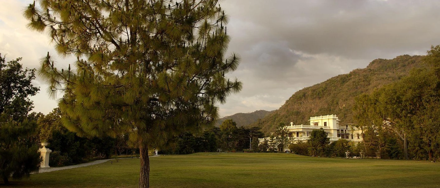 Colonial palace peering through tropical mountain greenery, fronted by a lawn