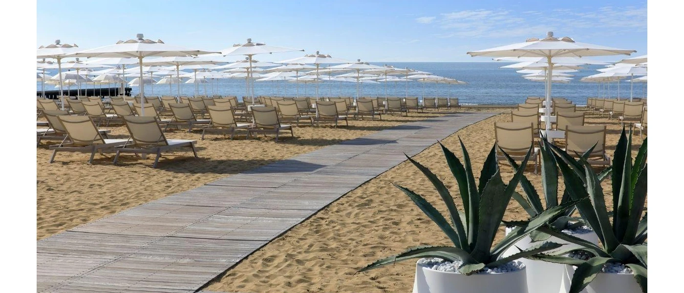 Wooden walkway on a beach furnished with loungers and parasols 