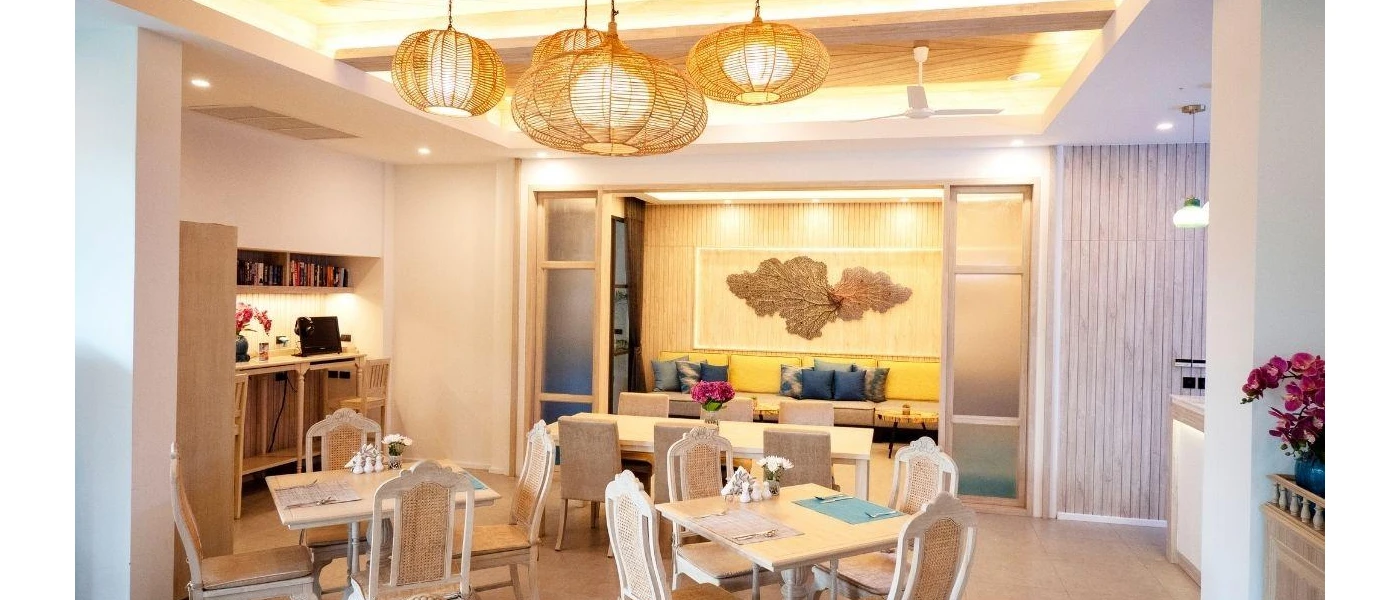 Bohemian-style restaurant with rattan pendant lights, a sofa with yellow and blue cushions and light-wood tables and chairs