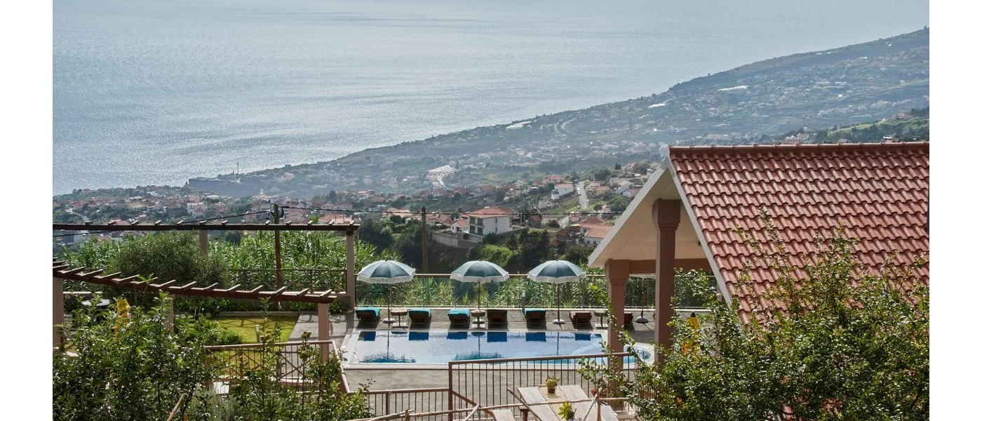 Swimming pool and umbrellas on a terrace with views of the surrounding countryside