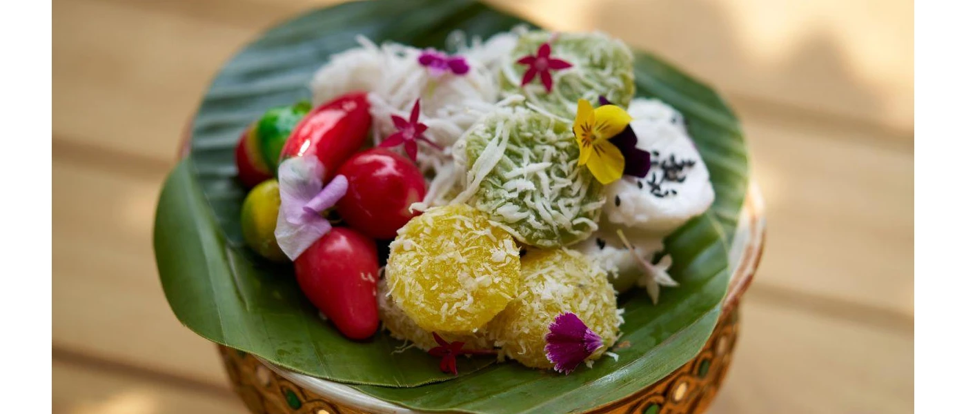 Bowl with a green leaf topped with sweets, fruit and edible flowers